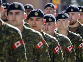 A female member, centre, of the Canadian Forces marches with fellow soldiers during the Calgary Stampede parade in Calgary, Friday, July 8, 2022.