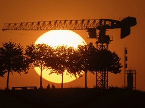 A couple lingers on the Kronsberg at the end of a hot day while the sun sets on the horizon in Hanover, Germany, Tuesday, July 19, 2022.