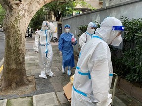 Workers in protective suits walk on a street, following the COVID-19 outbreak, in Shanghai, China, June 9, 2022.