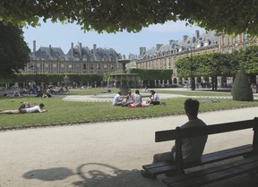 A man sits on a bench in a park at the centre of the Place des Vosges, in the Marais district, in Paris. Jacques Brinon/AP