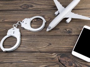 handcuffs, model airplane, smartphone on a wooden background.