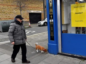A man walks his dog past a pharmacy advertising coronavirus disease (COVID-19) booster shots availability, in Dublin, Ireland, January 25, 2022.