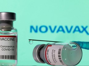 Vials labelled "VACCINE Coronavirus COVID-19" and a syringe are seen in front of a displayed Novavax logo in this illustration taken Dec. 11, 2021.