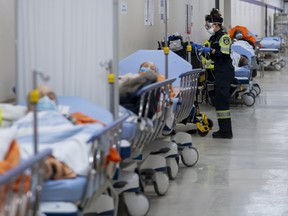 Paramedics transfer patients to the emergency room triage but have no choice but to leave them in the hallway due to an at capacity emergency room at the Humber River Hospital during the COVID-19 pandemic in Toronto on Tuesday, January 25, 2022. THE CANADIAN PRESS/Nathan Denette