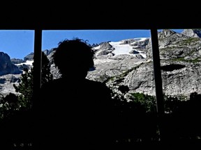 A person looks from the window of Castiglioni refuge at the Punta Rocca glacier that collapsed near Canazei, on the mountain of Marmolada, after a record-high temperature of 10 degrees Celsius was recorded at the glacier's summit, Tuesday, July 6, 2022.