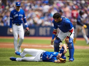 Blue Jays starter Kevin Gausman lays injured on the field after being hit by a ball as catcher Gabriel Moreno, right, tends to him during MLB action against the Rays at the Rogers Centre in Toronto, Saturday, July 2, 2022.