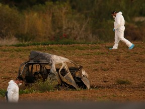 Forensic experts walk in a field after a powerful bomb blew up a car and killed investigative journalist Daphne Caruana Galizia in Bidnija, Malta, October 16, 2017.