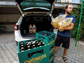 Moritz Baller unloads sunflower oil from Ukraine, a total of 80 litres, from the trunk of his car at Munich's Giesinger Braeu Brewery in Munich, Germany, Friday, July 15, 2022.