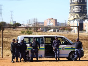 Police officers keep watch as South African Police Minister Bheki Cele arrives at the scene where 15 people were killed in a hail of at least 137 bullets by unknown gunmen inside a tavern, in Nomzamo informal settlement, in Soweto, Johannesburg, South Africa, July 11, 2022.