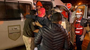 Mexikanische Behörden helfen einem verletzten Migranten, in ein Fahrzeug des Nationalen Instituts für Migration (INM) zu steigen, nachdem er zusammen mit anderen Migranten gerettet wurde, die am 27. Juli 2022 in der Stadt Acayucan im mexikanischen Bundesstaat Veracruz in einem Wohnwagen zurückgelassen wurden.