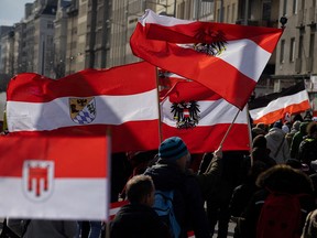 People carry Austrian flags as they march during a demonstration against COVID-19 measures in Vienna, Austria March 20, 2021.