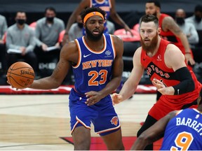 Dec 31, 2020; Tampa, Florida, USA; New York Knicks center Mitchell Robinson (23) passes the ball as Toronto Raptors center Aron Baynes (46) defends during the first quarter at Amalie Arena.