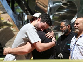 Friends hug the family members of Gregory Girgis, 26, on July 2 at the crash scene where Girgis was killed.