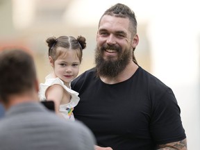 Former Denver Broncos defensive lineman Derek Wolfe, right, holds a child as he is greeted by members of the media as he attends NFL football team training camp on Friday, July 29, 2022, in Centennial, Colorado. Wolfe signed a one-day contract with the Broncos to retire as a Denver player on Friday.
