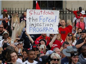 A person holds a sign across from Parliament Hill as a protest against COVID-19 mandates takes place on Canada Day, in Ottawa, Ontario, Canada July 1, 2022.