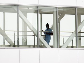 A health-care worker crosses a covered overhead walkway at a hospital in Montreal, Tuesday, Aug. 17, 2021.