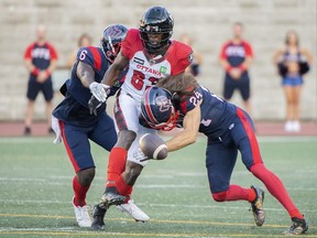 Ottawa Redblacks' Llevi Noel, centre, is tackled by Montreal Alouettes' Davis Alexander (6) and Marc-Antoine Dequoy (24) during first half CFL pre-season football action against the Montreal Alouettes in Montreal, Friday, June, 3, 2022.