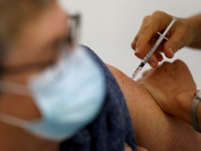A medical worker administers a dose of the "Cominarty" Pfizer-BioNTech coronavirus disease (COVID-19) vaccine to a patient at a vaccination center in Ancenis-Saint-Gereon, France, November 17, 2021.