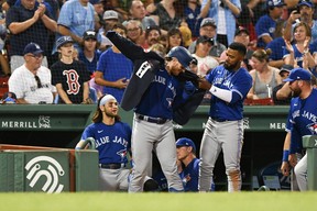 Toronto Blue Jays No. 37 Teoscar Hernandez places a jacket on No. 9 Danny Jansen after Jansen hit a two-run homer against the Boston Red Sox in the sixth inning at Fenway Park on July 22 2022 in Boston, MA.