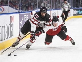 Canada's Shane Wright (15) and Austria's Tobias Sablattnig (12) battle for the puck during second period IIHF World Junior Hockey Championship action in Edmonton on Tuesday, December 28, 2021.