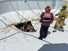 In this photo provided by Israel Fire and Rescue Services, Israeli firemen and rescuers work in a sinkhole formed in a swimming pool in Karmi Yosef, Israel, Thursday, July 21, 2022.