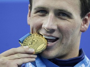 Ryan Lochte bites his gold medal for the men's 200 metre freestyle at the FINA Swimming World Championships in Shanghai, China, on July 26, 2011.