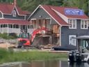 A person on an excavator is seen plowing through the Pride of Rosseau Marina.