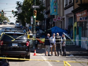 A member of the Independent Investigations Office (IIO) speaks to other investigators at the scene of a police involved shooting in the Downtown Eastside of Vancouver, on Saturday, July 30, 2022.