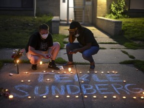 Marcia Howard, activist and George Floyd Square caretaker, right, takes a moment as she lights candles during a vigil for 20-year old Andrew Tekle Sundberg Thursday, July 14, 2022.