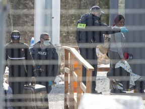 Asylum seekers cross the border from New York into Canada at Roxham Road Wednesday, March 18, 2020, in Hemmingford, Quebec.