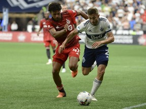 Jul 26, 2022; Vancouver, BC, Canada;  Vancouver Whitecaps FC defender Marcus Godinho moves the ball against Toronto FC midfielder Kosi Thompson during the second half at BC Place.