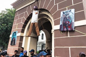 Aktivisten stehen am 10. Juli 2022 in Colombo unter einem Bildnis des srilankischen Präsidenten Gotabaya Rajapaksa, das an einem Uhrenturm in der Nähe seines Amtssitzes hängt.