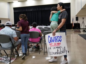 Rachel Martinez carries her son and a protest sign as she attends a city council meeting in Uvalde, Texas on July 12, 2022.