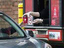 A Tim Hortons employee hands out coffee from a drive-through window to a customer in Mississauga, Ont., on Tuesday, March 17, 2020.
