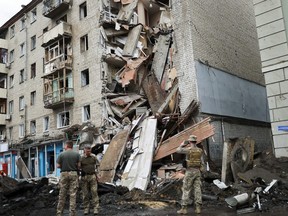 Ukrainian servicemen stand in front of Valentina Popovichuk's flat, where she was rescued after Russian shelling in a military strike, as Russia's invasion of Ukraine continues, in Kharkiv, Ukraine, July 11, 2022.