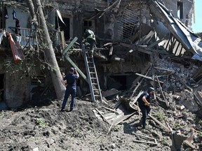 Ukrainian rescuers and security personnel work outside a residential building destroyed by a missile strike in Kharkiv, on July 9, 2022.