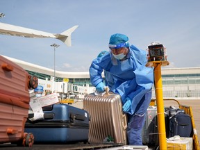 A worker, wearing a protective suit following the coronavirus disease (COVID-19) outbreak, transports luggage on the tarmac of Wuhan Tianhe International Airport, on a hot summer day in Wuhan, Hubei province, China July 14, 2022.