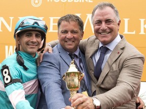 Jockey Rafael Hernandez (left), trainer Kevin Attard (centre) and owner Donato Lanni celebrate the Queen's Plate victory by Moira on Aug. 21, 2022.