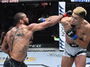 In this handout photo provided by UFC, (L-R) Thiago Santos of Brazil punches Johnny Walker of Brazil in their light heavyweight bout during the UFC Fight Night event at UFC APEX on October 02, 2021 in Las Vegas, Nevada.