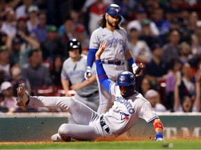 Lourdes Gurriel Jr. of the Toronto Blue Jays slides into home to score against the Boston Red Sox during the third inning at Fenway Park on August 23, 2022 in Boston, Massachusetts.