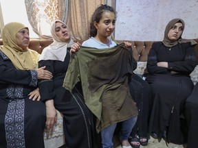 Sister of Palestinian Mohammed al-Shaham, 21, killed during an Israeli home raid, carries her brother's bloodied shirt as she mourns with his mother (2nd L) and other women at their family home in Kafr Aqab town, in Israeli-annexed east Jerusalem, on August 15, 2022.