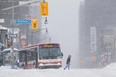 A pedestrian crosses the street as a city bus is pictured stuck during a winter storm in Toronto on Monday, Jan. 17, 2022.