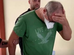 A screen grab from a video shows Brazilian police officers escorting Uwe Herbert Hahn, German consul in Rio de Janeiro, following his arrest for the alleged murder of his husband, in Rio de Janeiro, Brazil, August 7, 2022.