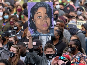In this file photo taken on March 13, 2021, a protestor brandishes a portrait of Breonna Taylor during a rally in remembrance on the one year anniversary of her death in Louisville, Kentucky.
