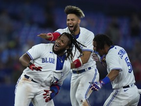 Toronto Blue Jays first baseman Vladimir Guerrero Jr. (27) reacts with teammates Lourdes Gurriel Jr. (13) and Santiago Espinal (5) after hitting the game winning RBI single to defeat the Baltimore Orioles during tenth inning American League, MLB baseball action in Toronto on Wednesday, June 15, 2022.