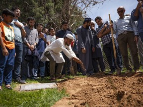 People sprinkle dirt over the grave of Muhammad Afzaal Hussain, 27, at Fairview Memorial Park in Albuquerque, N.M., on Friday, Aug. 5, 2022.