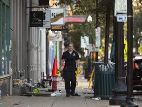 A Cincinnati police officer clears police tape and casing markers,, Sunday, Aug. 7, 2022, in Cincinnati, following an overnight shooting.