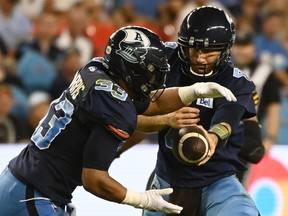 Toronto Argonauts quarterback McLeod Bethel-Thompson hands off the ball to running back Andrew Harris during second half CFL football action against the Hamilton Tiger-Cats in Toronto on August 6, 2022. The Toronto Argonauts will be without Canadian running back Andrew Harris and American receiver Cam Phillips when they host the Calgary Stampeders on Saturday night. Harris, 35, is expected to miss four-to-six weeks with a torn pectoral muscle. Harris had three carries for 19 yards before leaving Toronto's 34-27 loss to the Hamilton Tiger-Cats last weekend in the first half.