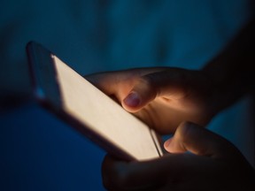 Little girl lying on bed and using smart phone late at night.