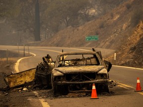 The charred remnants of a car towing a trailer that burned when fire jumped the Klamath River remain on the highway at the McKinney Fire in the Klamath National Forest northwest of Yreka, California, on July 31, 2022.